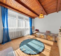 Ein Zimmer in einem Einfamilienhaus mit einem Boden in Holzoptik, blauen Vorhängen und einem großen Fenster.