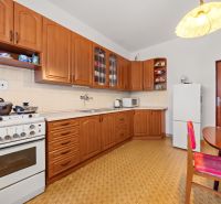 Küche in einem Einfamilienhaus mit Holzschränken, Herd und Esstisch.