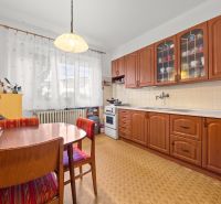 Eine Küche in einem Einfamilienhaus mit Holzmöbeldekor und Vorhängen an den Fenstern.