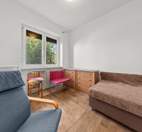 Ein Zimmer mit einem großen Fenster, einem Stuhl, einer Kommode und einem Boden mit Holzdekor in einem Einfamilienhaus.