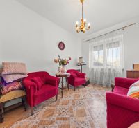 Wohnzimmer in einem Einfamilienhaus mit roten Sesseln und einem Tisch auf einem Boden mit Holzdekor.
