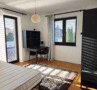 Schlafzimmer im Einfamilienhaus mit Holzboden, Schreibtisch und Teppich.