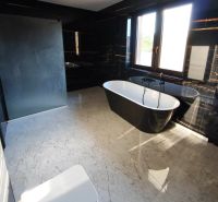 Elegantes Badezimmer mit freistehender Badewanne und schwarzen Wänden in einem Einfamilienhaus.