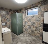 Ein Badezimmer in einem Einfamilienhaus mit gemusterten Fliesen und einer Duschkabine.