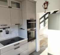 Küche in einem Einfamilienhaus mit eingebautem Ofen, grauen Schränken und Induktionskochfeld.
