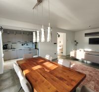 Esstisch aus Massivholz in einem Einfamilienhaus mit Küche und Wohnzimmer auf einem Boden mit Holzdekor.