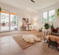 Wohnzimmer in einem Einfamilienhaus mit Pflanzen, großen Fenstern und angenehmer Beleuchtung.