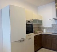 Küche in einer 3-Zimmer-Wohnung mit weißen und hölzernen Schränken und Geräten.