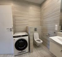 Badezimmer mit Waschmaschine und Toilette in einer 3-Zimmer-Wohnung, Fliesen mit Steinmuster.