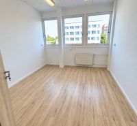 Ein Büro mit einem Boden in Holzoptik, Innenraum mit großen Fenstern und Deckenbeleuchtung.