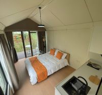 Eine Hütte mit Holzboden, ein einfaches Bett, eine kleine Küche und ein Balkon.