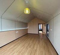 Innenraum einer Hütte mit Holzboden und einer auffälligen Hängelampe.