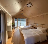 Ein Schlafzimmer in einer Hütte mit zwei Betten und einem Boden in Holzoptik, mit Blick auf den See.