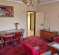 Wohnzimmer mit Blumendekor in einem Einfamilienhaus, rote Sessel, gemusterter Teppich.