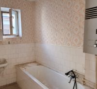 Badezimmer im Einfamilienhaus mit Badewanne, Waschbecken und Gasboiler.