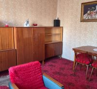 Wohnzimmer eines Einfamilienhauses mit Retro-Möbeln, rotem Teppich und tapezierten Wänden.
