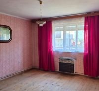 Ein Zimmer in einem Einfamilienhaus mit rosa Tapeten und einem Boden in Holzoptik.