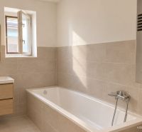 Ein Badezimmer in einem Einfamilienhaus mit einer Badewanne, einem Spiegel und einem Fenster, Boden mit Holzdekor.