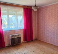 Ein Zimmer in einem Einfamilienhaus mit Tapeten, roten Vorhängen und einem Boden in Holzoptik.