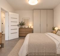 Schlafzimmer mit hellen Möbeln, Schreibtisch und Dekorationen in einer 2-Zimmer-Wohnung.