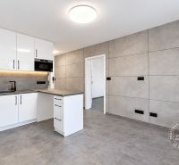 Küche in einer 2-Zimmer-Wohnung mit weißer Küchenzeile und grauen Fliesen.