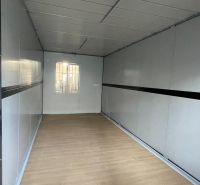 Das Innere der Hütte mit einem Boden in Holzoptik, weißen Wänden und einem kleinen Fenster.