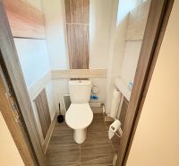 Toilette im Einfamilienhaus mit Keramikfliesen und schmalem Fenster.