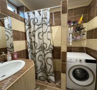 Badezimmer in einem Einfamilienhaus mit Waschbecken, Duschkabine und Waschmaschine.