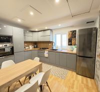 Küche in einem Einfamilienhaus mit Holzboden, weißen Stühlen und Geräten.