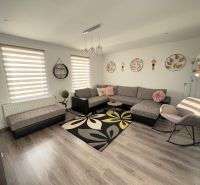 Wohnzimmer eines Einfamilienhauses mit Wand- und Bodendekor in Holzoptik.