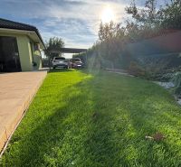 Der Garten beim Einfamilienhaus in der Feigenstraße in Bernolákovo mit einem sonnigen Wohnsitz und Grünflächen.