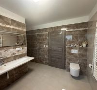 Badezimmer im Einfamilienhaus mit großem Spiegel und Fliesen mit Marmormuster.