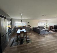 Offenes Interieur eines Einfamilienhauses mit Küche, Esstisch, Sofa und Holzboden.