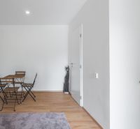Einfaches Interieur mit Holztisch und Stühlen auf einem Boden mit Holzdekor.