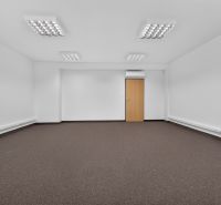 Ein geräumiges Büro mit weißen Wänden und braunem Teppich.