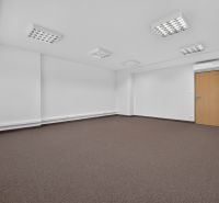 Ein leeres Büro mit braunem Teppich und weißen Wänden, der Raum ist beleuchtet und klimatisiert.