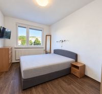 Schlafzimmer in einer 4-Zimmer-Wohnung mit Holzboden und großem Fenster.