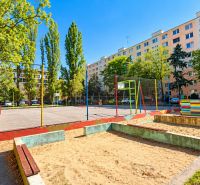 Ein Spielplatz umgeben von Grünflächen und Plattenbauten in der Rumančekova-Straße, Bratislava - Ružinov.