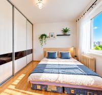 Helles Schlafzimmer mit Bett und großem Kleiderschrank in einer 3-Zimmer-Wohnung, Boden mit Holzdekor.