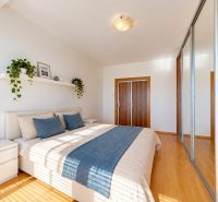 Helles Schlafzimmer in einer 3-Zimmer-Wohnung mit Bett, Holzboden und Spiegelschrank.