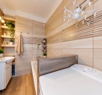 Badezimmer in einer 3-Zimmer-Wohnung mit Holzboden, Badewanne und Waschmaschine.