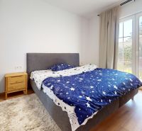 Schlafzimmer in einer 2-Zimmer-Wohnung mit Doppelbett, Nachttischen und Boden in Holzoptik.