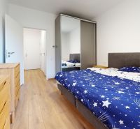 Schlafzimmer mit Bett, Einbauschrank und Boden mit Holzdekor in einer Zweizimmerwohnung.