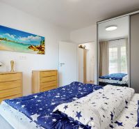 Schlafzimmer in einer 2-Zimmer-Wohnung mit Holzboden, weißen Wänden und einem Bild von einem Strand.