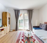 Wohnzimmer einer Zweizimmerwohnung mit Sofa, Fernseher und Holzboden.