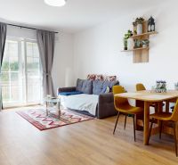 Wohnzimmer mit Sofa, Esstisch und Holzboden in einer Zweizimmerwohnung.