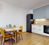 Küche in einer 2-Zimmer-Wohnung mit Holzboden, Esstisch und Geräten.
