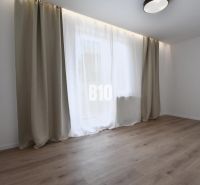 Helles Zimmer mit Holzboden und großem Fenster in einer 4-Zimmer-Wohnung.