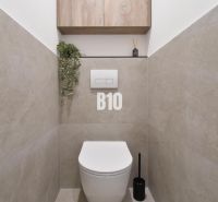 Badezimmer mit hängendem WC, Boden in Holzoptik und Stauraum.