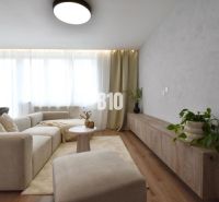 Wohnzimmer in einer 4-Zimmer-Wohnung mit Sofa, Tisch und Boden in Holzoptik.